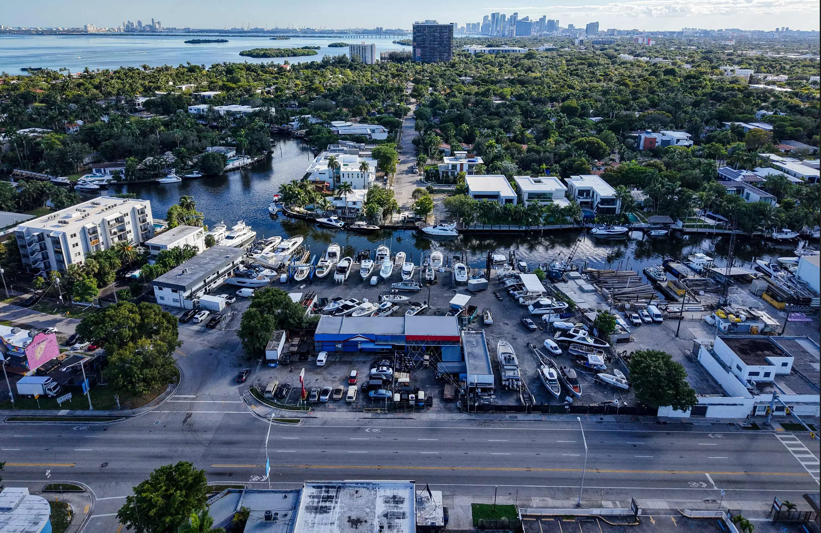 Aerial view of 830 NE 79th St, Miami, showing the property along the canal with the Miami skyline in the background.